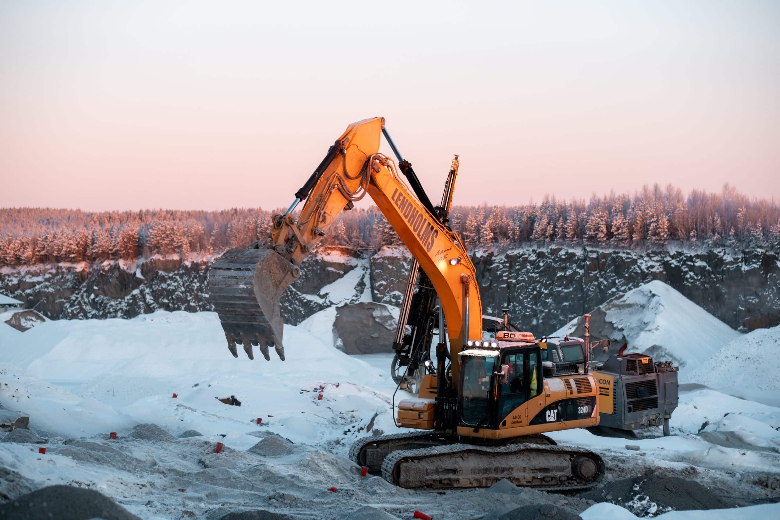 Grävmaskin i snöigt landskap